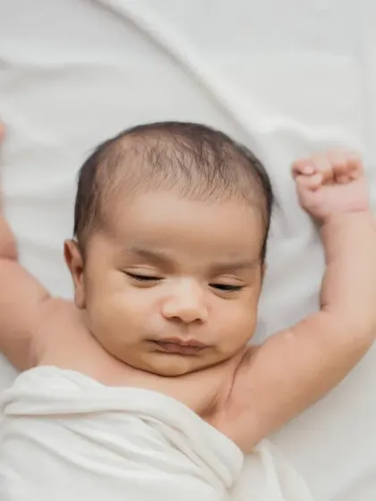 The color version of the sleepy stretch, showing the baby's beautiful skin tone against the soft white fabric.