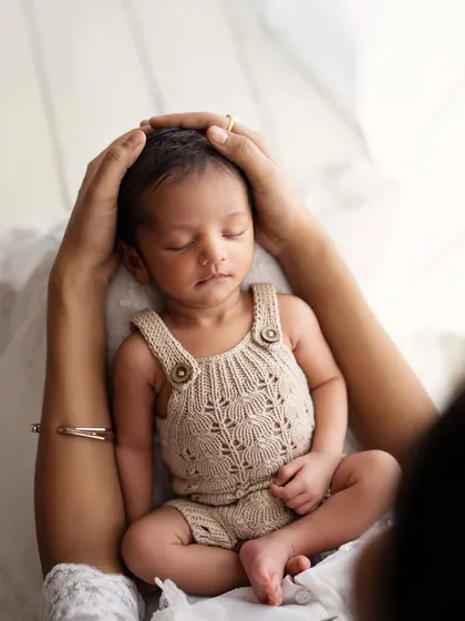 A mother's hands gently cradling her baby's head. This shot is all about protection, safety, and unconditional love.