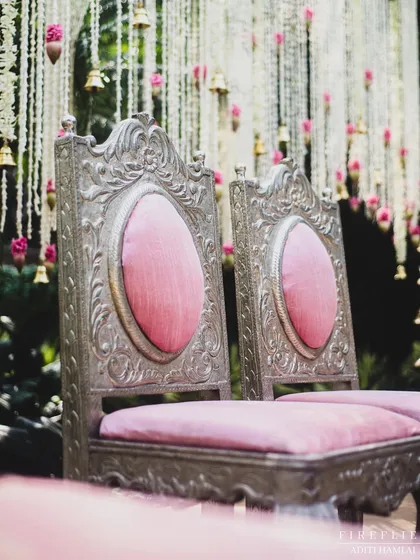 The ornate, silver-carved chairs for the bride and groom at the 'Tree of Love' mandap. The pink upholstery perfectly complements the floral decor.