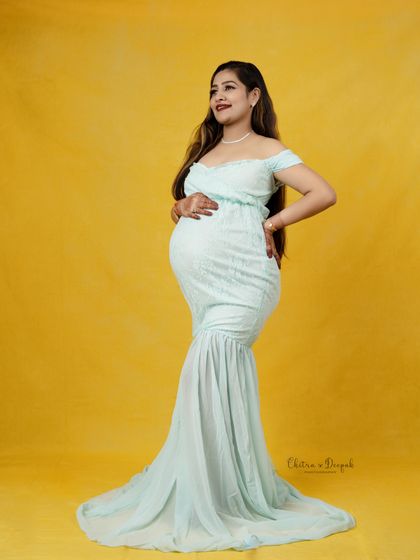 Sunshine and serenity. This mom-to-be looks radiant in a light blue mermaid-style gown against a cheerful yellow backdrop, a perfect combination for a happy pregnancy photo.