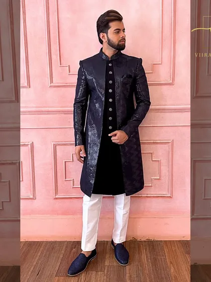 A full shot of the navy blue sherwani against a pink backdrop, showing its versatility and style. This is a great custom option for grooms and their family members.