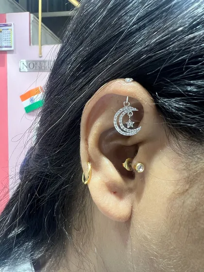 A celestial-themed ear featuring a moon and star hanging from the helix. This dreamy combination is perfect for those who love stargazing.