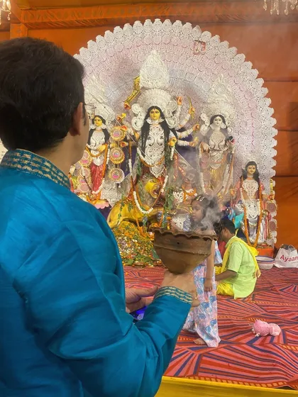 A devotee in traditional attire performs the Dhunuchi dance in front of the beautifully decorated Durga idol. It's a moment of pure, uninhibited worship.