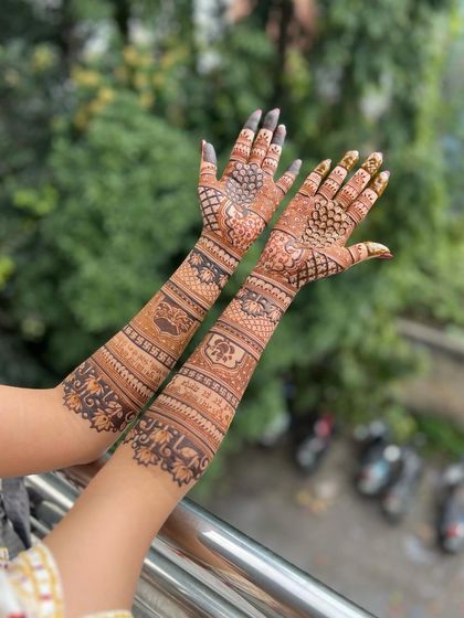 A full-arm design captured outdoors, with the natural background making the henna details stand out.