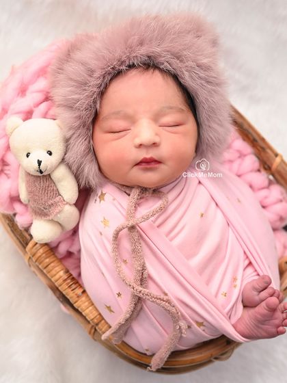 A repeat of a lovely pose, this image shows the baby girl sleeping peacefully in her pink furry hood, a perfect example of a cozy setup.