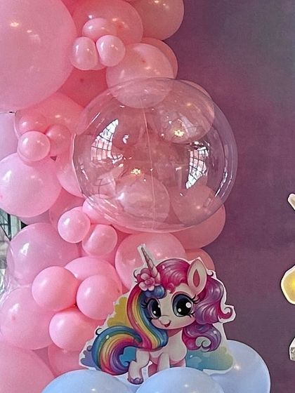 A close-up of a pink balloon garland with a cute unicorn cutout. This highlights the small details that make a themed party special, including the clear bubble balloon for added texture.
