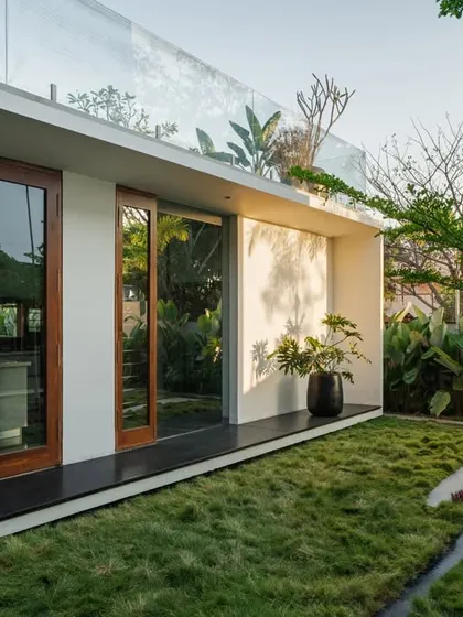 The connection to the outdoors is paramount in our designs. Here, full-height glass doors slide away to merge the interior with a private lawn, embodying the principles of tropical modern living.