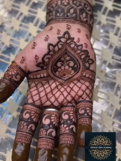 This design features a bold, symmetrical motif in the center of the palm, surrounded by a net pattern. The dark, filled fingertips provide a classic bridal finish.