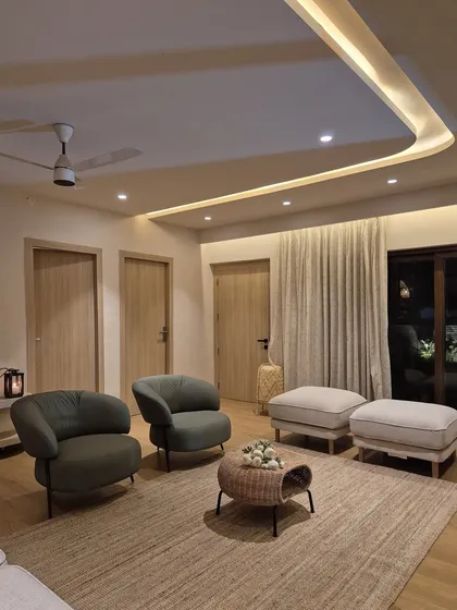 This seating nook in the Coorg villa is arranged for conversation and comfort. We used plush armchairs, a natural fiber rug, and soft cove lighting to create an intimate and cozy corner within the larger living space.