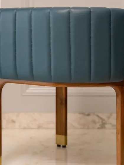 A close-up of the back of our artistic accent chair, revealing the channel-stitched leather and the smooth, curved teakwood frame. Every detail is crafted to tell a story of quality.
