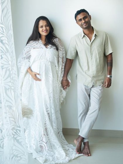 A beautiful, light-filled portrait of the couple holding hands. The delicate white lace gown and their relaxed poses create a fresh and modern feel for this at-home session.