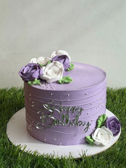 Another view of our elegant purple floral cake, showcasing the beautiful arrangement of hand-piped whipped cream roses.
