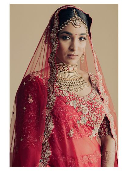 A close-up bridal portrait in a stunning red lehenga. Her direct gaze is powerful and confident, showcasing the modern bride's strength and grace.