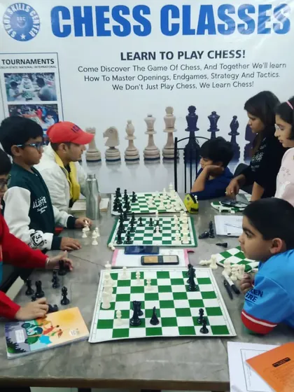 An instructor observes and guides students during a chess class. We provide proper study materials and a structured learning environment to help every child master the game.