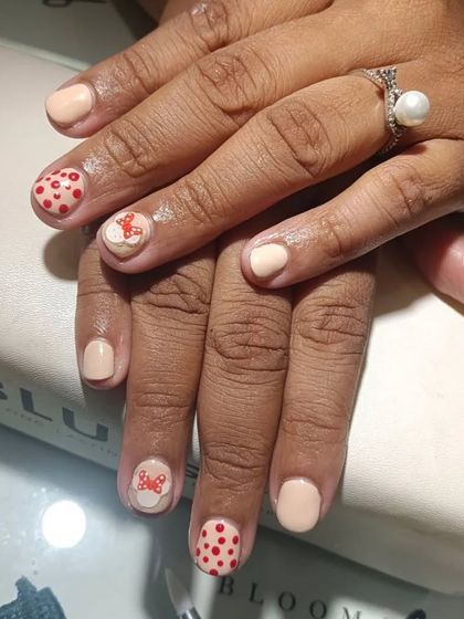 A client who is a neurologist wanted Mickey Mouse on her nails. I loved creating this cute design with nude polish, polka dots, and a Minnie bow.