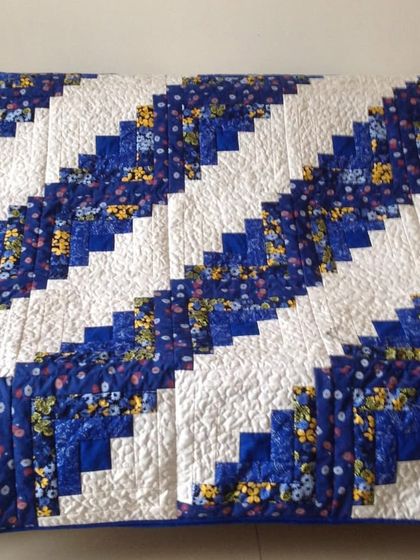 A Log Cabin quilt in blue and white, draped on a sofa.