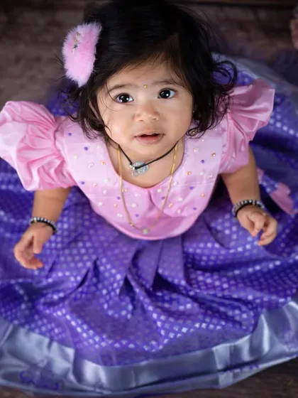 An expressive upward glance from this little darling. The high-angle shot beautifully displays the full skirt of her traditional dress.
