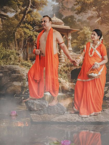 A unique, mythology-inspired couple shoot. Dressed in saffron-colored traditional attire, the couple recreates a scene reminiscent of Ram and Sita by a serene, misty pond.