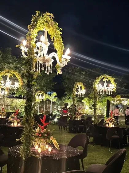 A wide view of our enchanting outdoor dinner setup, where each table is a world of its own under a personal, vine-wrapped chandelier.