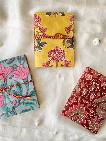 A vibrant set of three pocket-sized journals, perfect for carrying with you on the go. Each one has a unique and colorful block-print cover.