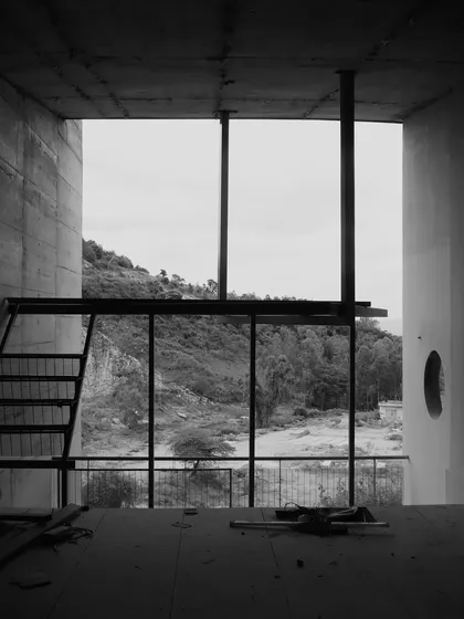 A view from inside one of the unfinished cottages, framing the rugged landscape and demonstrating the connection to nature.