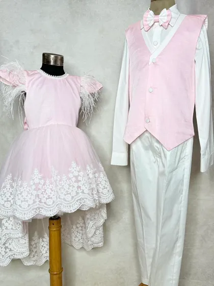Twinning for a special occasion. This photo shows a coordinated look with a pink and white suit for him and a matching high-low dress for her.