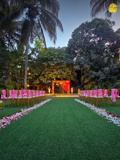 An evening ceremony setup on our lawn, with chairs adorned with pink ribbons, ready for guests to witness a beautiful union as the sun sets.
