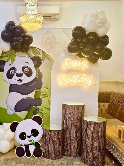 The panda party decor from the side, showing the log-themed pedestals for the cake and desserts.