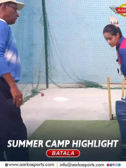 A female cricketer practices her batting stance under the watchful eye of a coach. Her focus and determination are commendable.