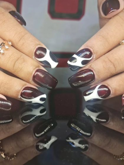 A full view of the sophisticated burgundy and white abstract swirl nail art.