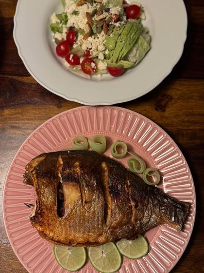 Another presentation of our whole roasted fish, this time on a pink plate with a side salad. The fish is scored to allow the marinade to penetrate deep into the flesh.
