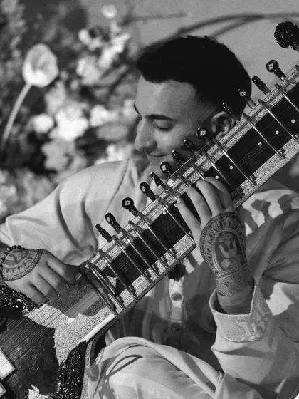 A black and white close-up of my hands on the sitar. The intricate henna designs are a form of 'Shringhar' or decoration, a way of celebrating the performance and honoring the tradition.