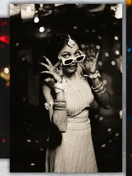 A stylish black and white photo of the bride. Her playful pose and sunglasses create a modern twist on the traditional Haldi ceremony portrait.