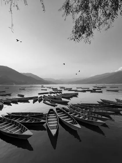 Stripped to black and white, the boats on the lake create a timeless, graphic scene. This monochrome photograph emphasizes the shapes, reflections, and quiet mood of the waterscape.