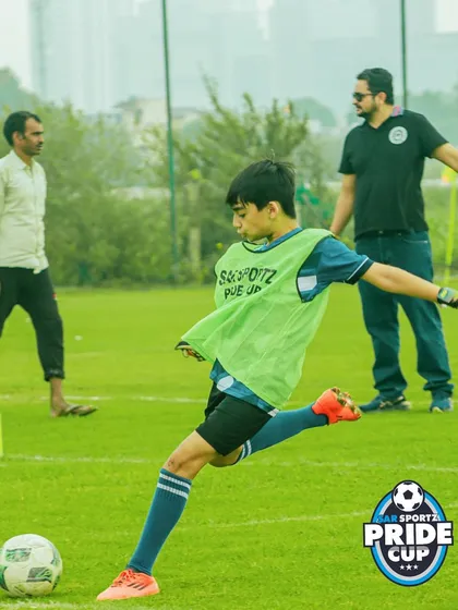 A player in a green training bib practices his shooting form, striking the ball with precision during a warm-up session at the Pride Cup.