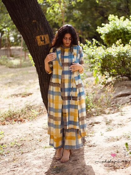 This image showcases the full three-piece co-ord set in a candid, natural pose. The soft lighting emphasizes the texture of the handloom fabric, while the full-body framing provides a clear view of the outfit's silhouette and proportions.