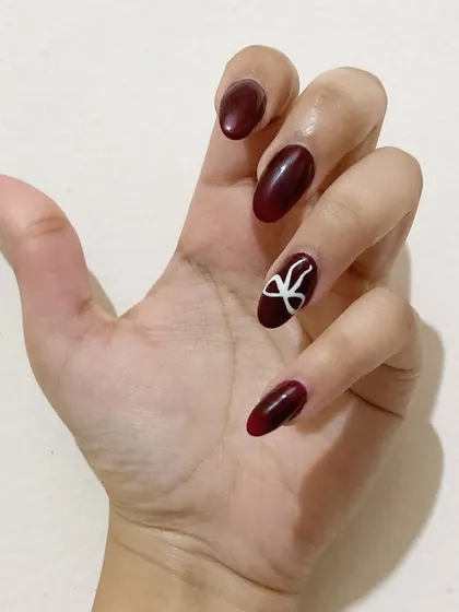 The perfect holiday manicure. This look combines classic deep red with a playful, hand-painted bow for a festive touch.