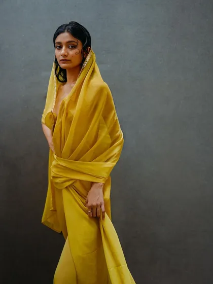 A full-length shot from the yellow drape series, showcasing a more structured styling of the fabric. The pose is strong and statuesque.