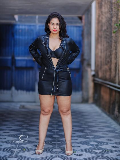 A full-length shot that showcases the entire edgy outfit. The patterned ground and blue background create a visually interesting and dynamic composition.