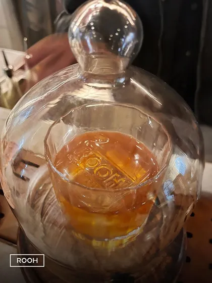 The reveal of our smoked Butter Old Fashioned. The glass cloche traps the aromatic smoke, which is released at your table for a moment of pure theatre.