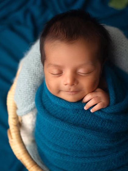 A sweet sleepy smile from this little boy, tucked into a basket. The contrast of the blue wrap against the natural basket fibers is just beautiful.