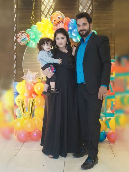 A family stands together for a photo at a birthday party, framed by a colorful Cocomelon-themed balloon arrangement.
