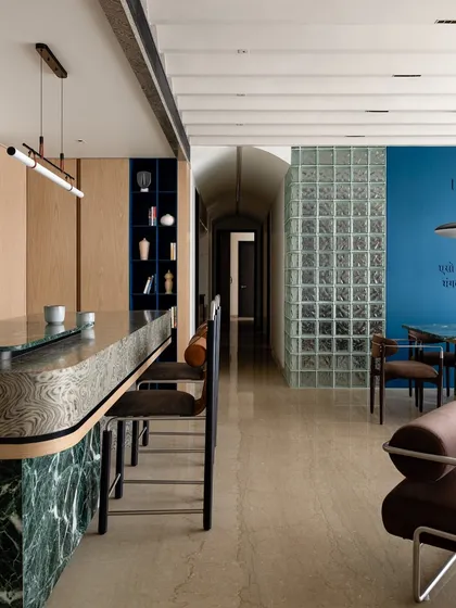 The open-plan layout of 'ARAH' is clearly visible here, with the breakfast bar, dining area, and living room flowing into one another. The arched passage in the background adds architectural interest.