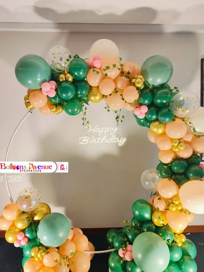 A closer look at the green and peach balloon arrangement, showing the details of the confetti balloons and floral accents.