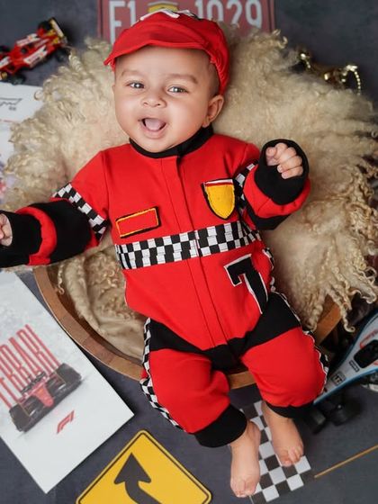 Ready, set, go! This little F1 driver is all smiles in his racing suit, surrounded by Ferrari and Monte Carlo props for a high-speed, super fun baby photoshoot.
