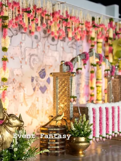 A closer view of the traditional naming ceremony stage. The decor is rich with details, including hanging floral garlands, brass Nandi statues, and a custom-painted backdrop, all creating a festive and sacred ambiance.