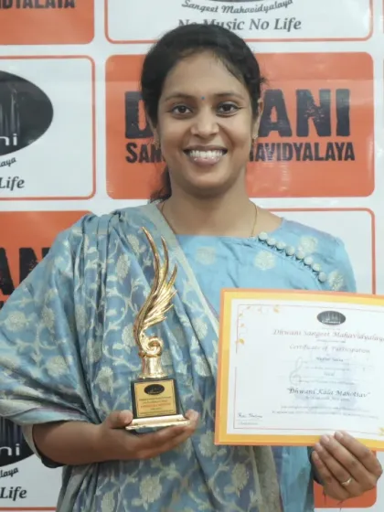An adult student proudly holds her certificate and trophy.