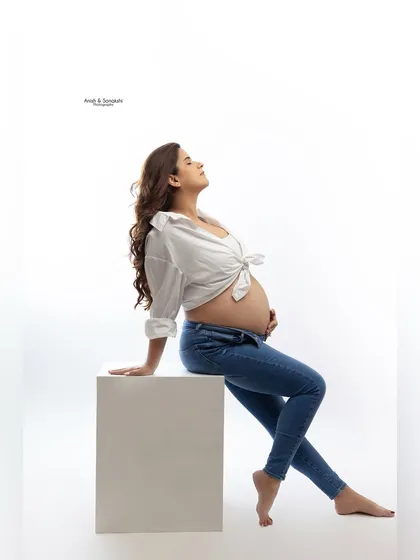Effortlessly chic and timeless. A classic white shirt and jeans can be just as powerful as a gown. This relaxed studio portrait focuses on the beautiful baby bump and the pure joy of pregnancy.