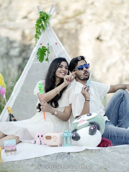 A playful pre-wedding picnic scene where the couple blows bubbles, surrounded by cute props and a teepee tent, capturing a lighthearted and joyful memory.