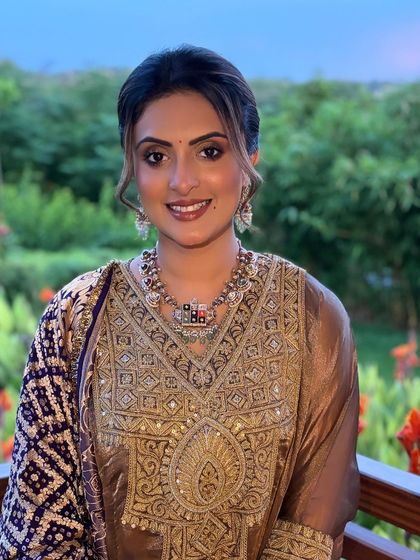 A portrait of the client, showing how the soft updo enhances her features and complements her elegant outfit and jewelry.